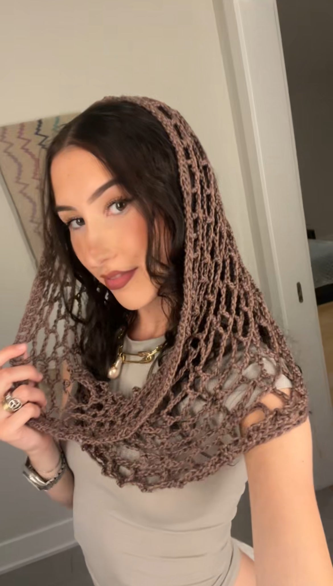 Taupe spiderweb crochet hood with hood crochet design, worn as a hood for festival, rave, or concert fashion.